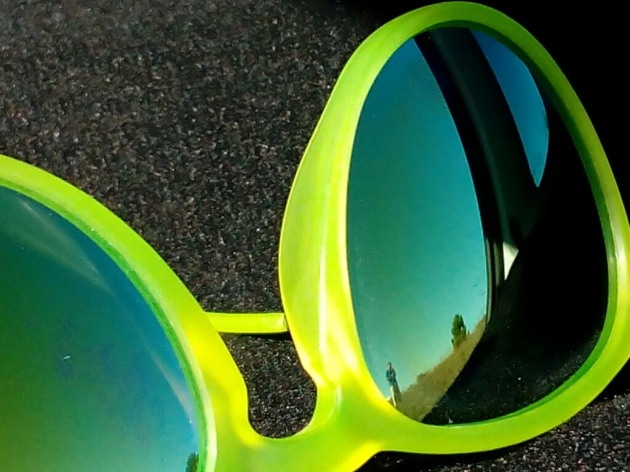 Eine neongelbe Sonnenbrille spiegelt sich im Sonnenlicht.