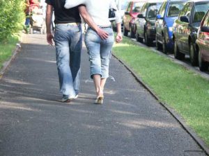 Mann und Frau laufen den Gehsteig entlang