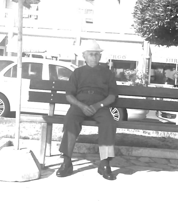 Ein alter Mann mit Hut sitzt auf einer Bank. Das Bild ist schwarz-weiß.